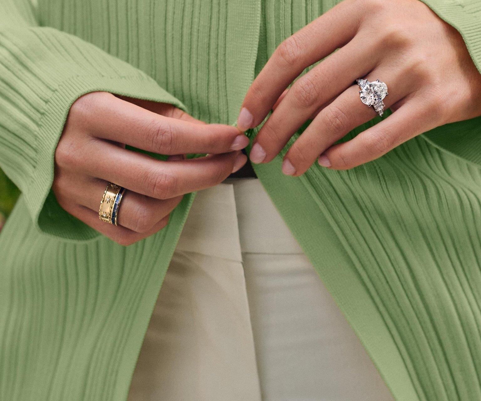 Model wearing diamond engagement ring and fashion rings.