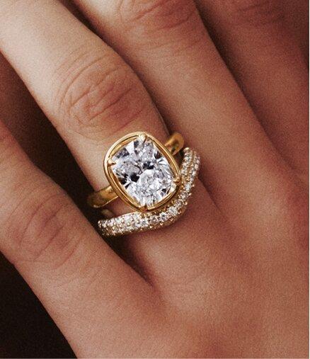Model wearing diamond bezel engagement ring and wedding ring.